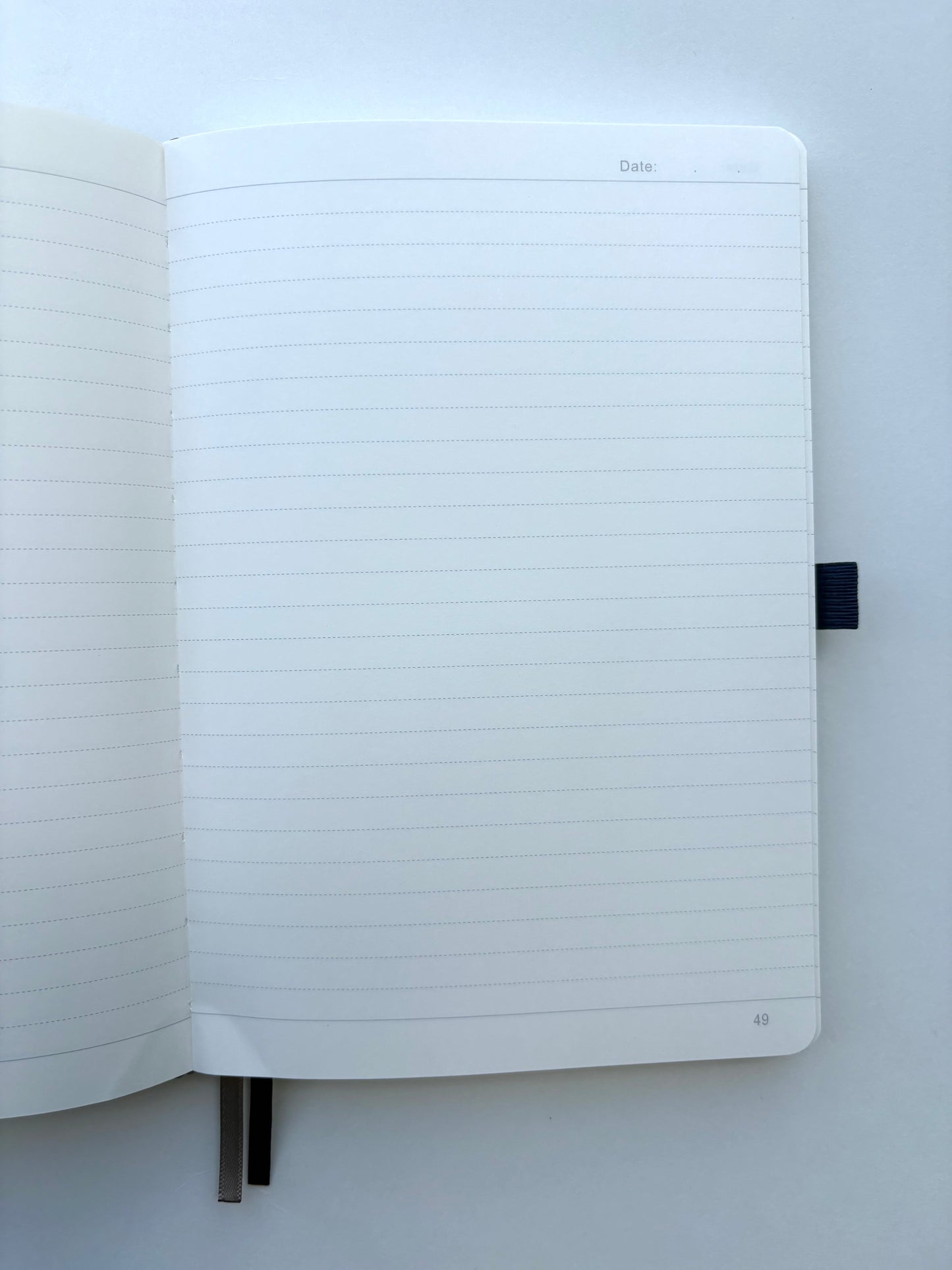 Inside pages of personalized black leather journal showing lined numbered pages, ribbon bookmarks, and premium paper