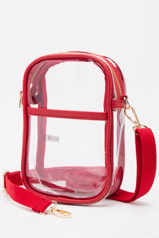 Clear crossbody bag with red trim, gold-tone hardware, and adjustable straps