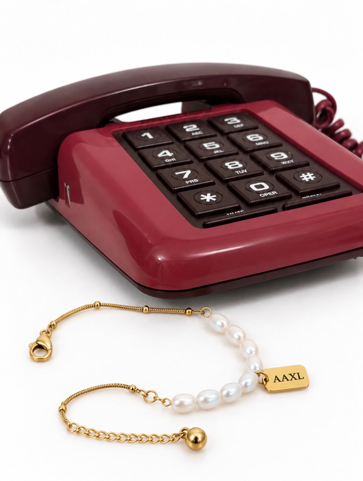 Personalized gold and pearl charm bracelet styled with burgundy vintage phone