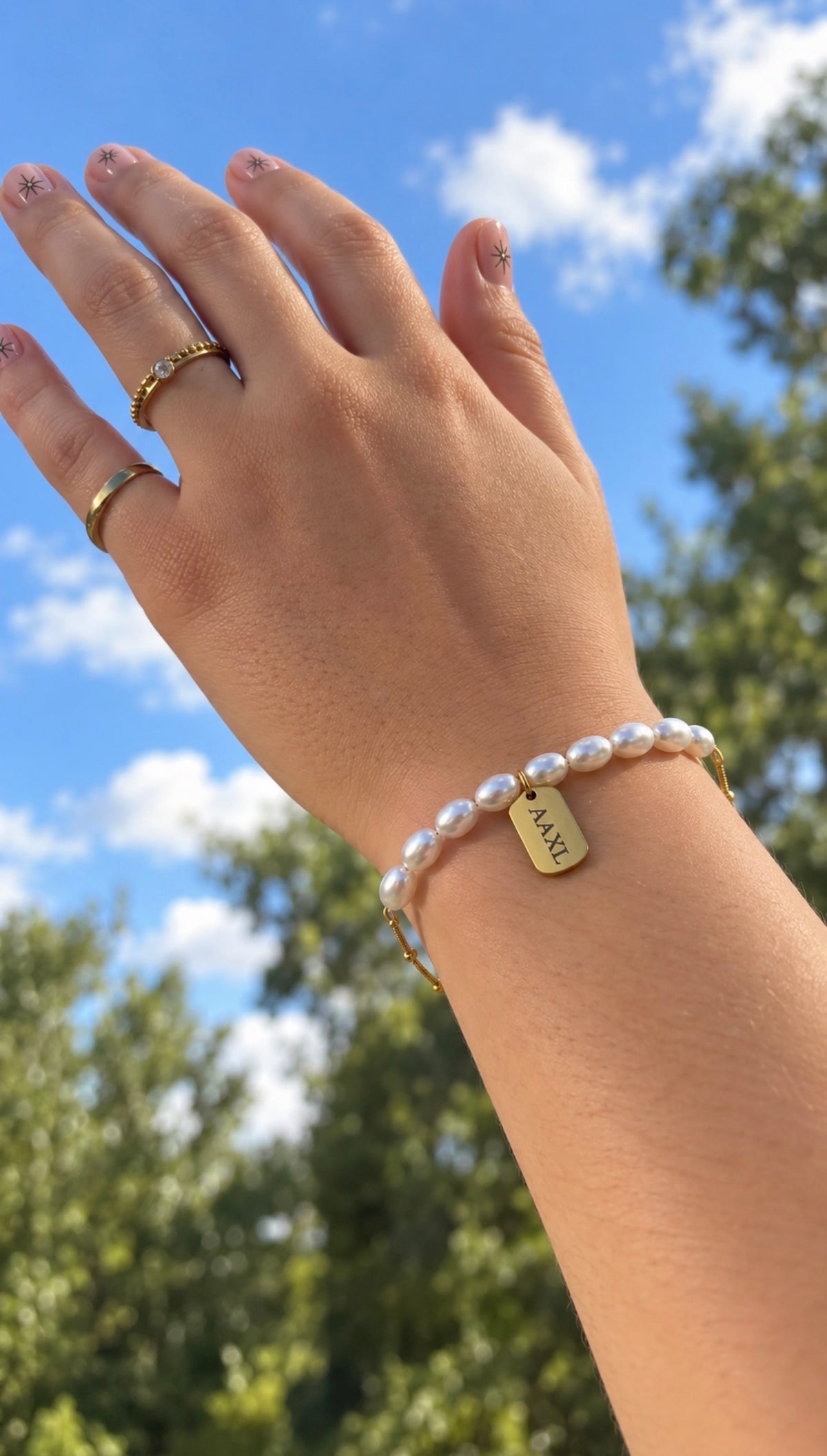 Personalized pearl Charm Me Bracelet worn on wrist with engraved AAXL charm