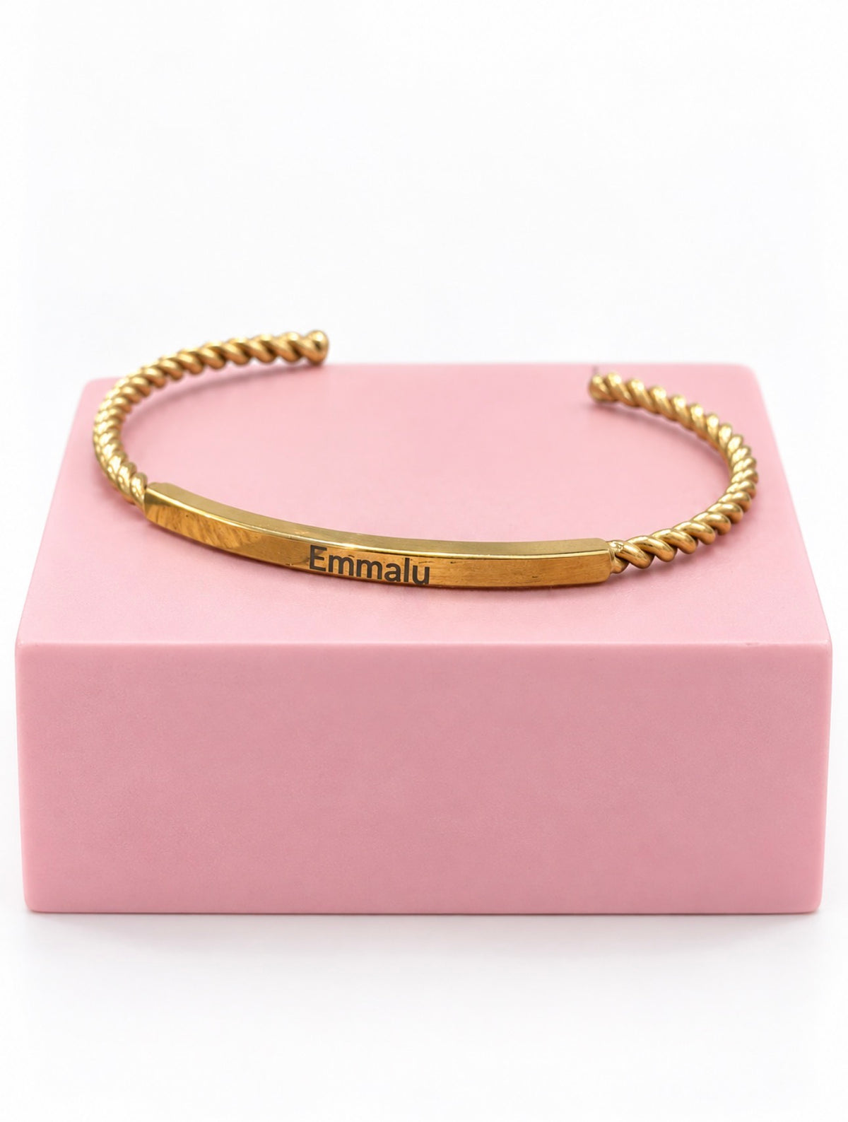 Personalized gold Gilded Cuff stainless steel bracelet engraved with Emmalu on pink pedestal