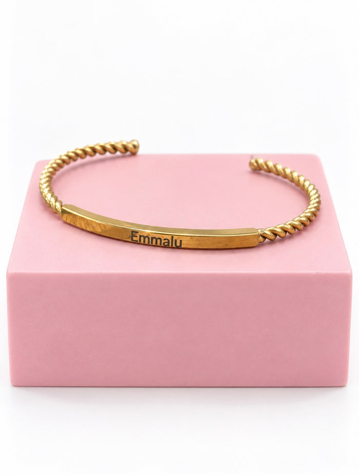 Personalized gold Gilded Cuff stainless steel bracelet engraved with Emmalu on pink pedestal