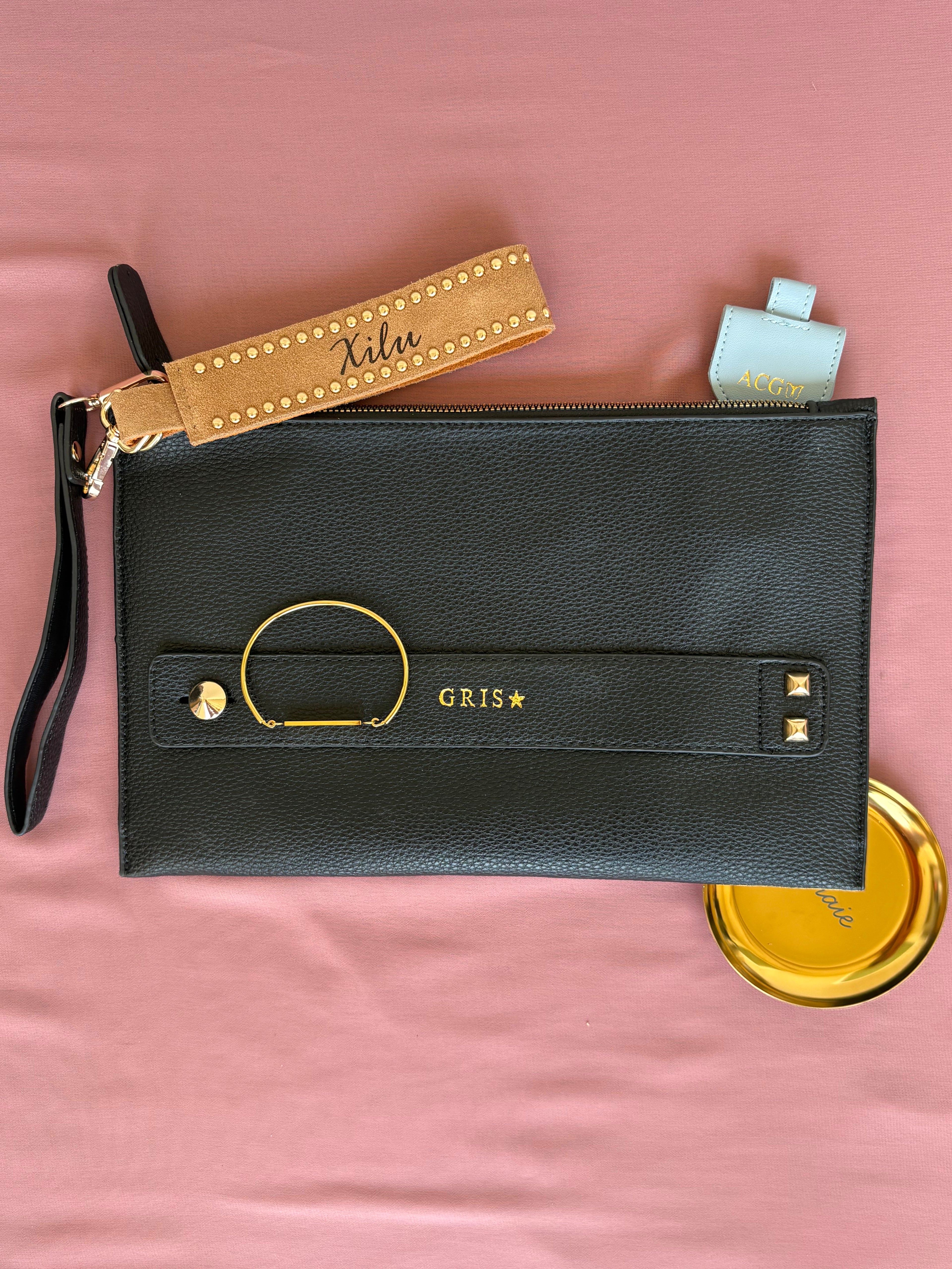 Personalized gifts including engraved bracelets, leather accessories, and keepsake items arranged in elegant pink fabric.