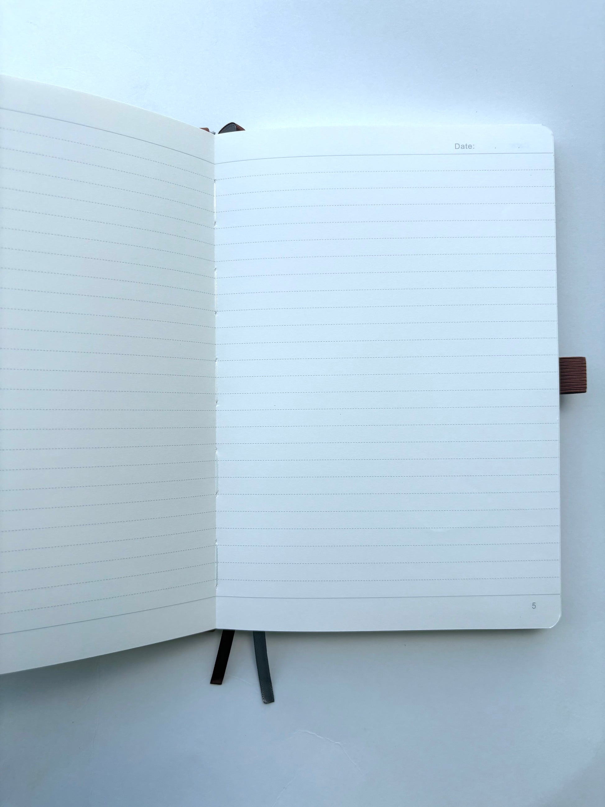 Inside pages of personalized brown leather journal featuring 192 numbered lined pages with ribbon bookmarks